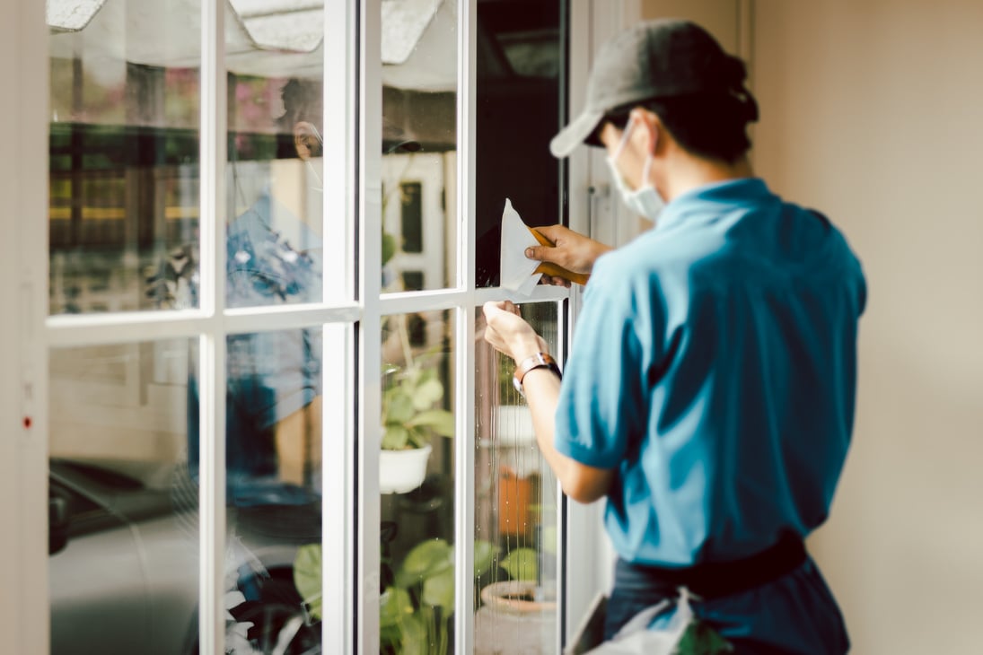 Man worker tinting window with foil indoor.