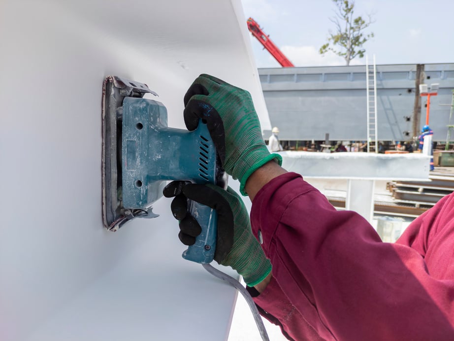 Using a Ponceuse Vibrante or Orbital Sander to scrub surface intermediate fire proof paint before painting top coat.